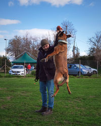 Man with dog on field against sky