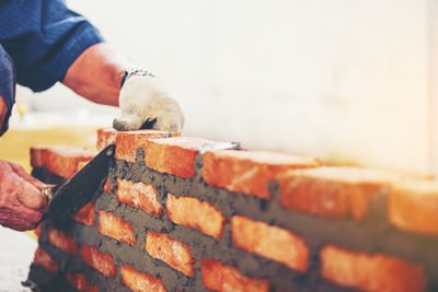 Cropped image of manual worker making brick wall at construction site