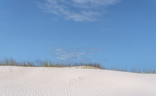 Scenic view of sand dunes against sky