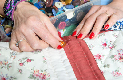 Close-up of hand holding button on quilt