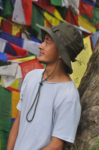 A asian young guy looking sideways, posing against buddhist prayer flags