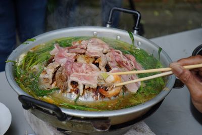 Close-up of person preparing food in cooking pan