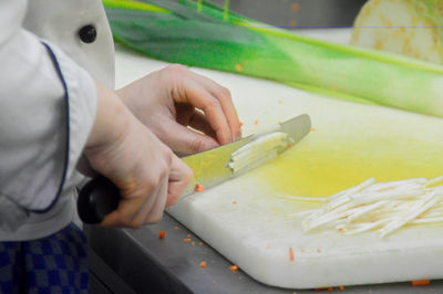 Cropped image of chef cutting vegetables on board