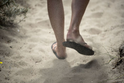 Low section of woman walking on sand