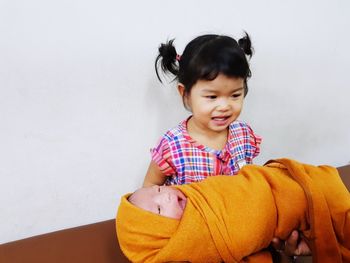 Cute girl carrying sister at home