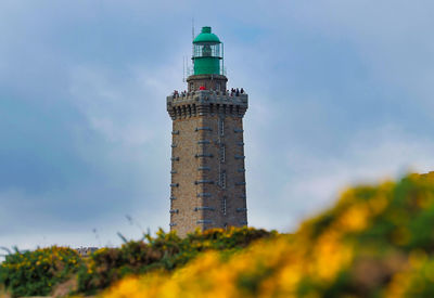 Low angle view of lighthouse by building against sky