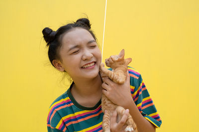 Portrait of smiling woman against yellow background