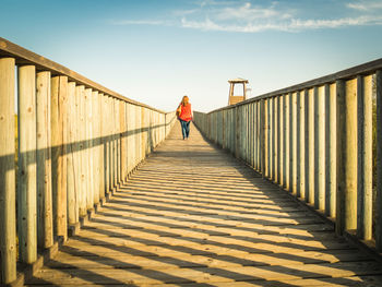 Rear view of woman walking on footbridge