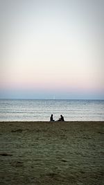 People on beach against clear sky