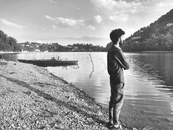 Side view of man fishing in river against sky