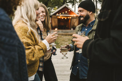 Cheerful women with friends drinking during social gathering