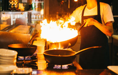 Midsection of chef preparing food in kitchen at restaurant