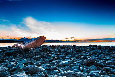 Surface level of rocks at beach against sky during sunset