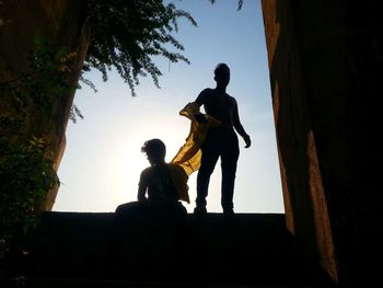 Silhouette of men against sky at sunset