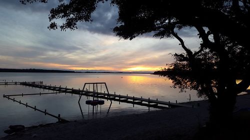 Silhouette plants by lake against sky during sunset