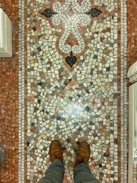 Low section of man standing on tiled floor