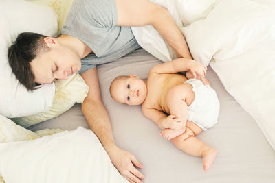 Father and baby sleeping on bed at home