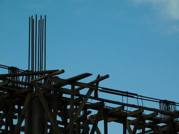 Low angle view of crane against clear blue sky