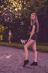 Portrait of beautiful woman standing on footpath with friend in background