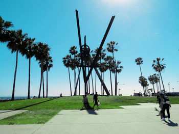 People walking at park against clear blue sky