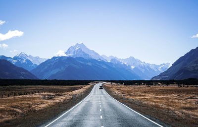 Empty road leading towards mountains against sky