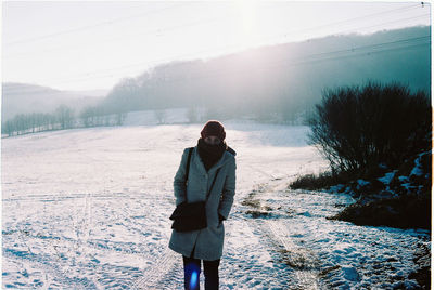 Woman standing on snow covered field against sky