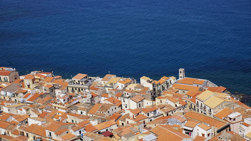 High angle view of townscape by sea against blue sky