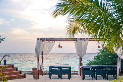 Chairs and tables at beach against sky