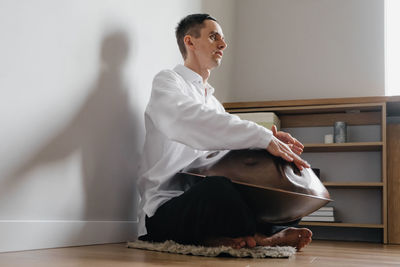 Man playing on hang drum, or steel drum, hangpan, modern steel music instrument at home. meditation