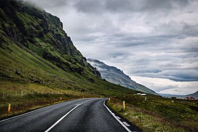 Road leading towards mountains against sky