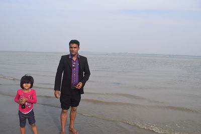 Full length portrait of happy boy standing on beach