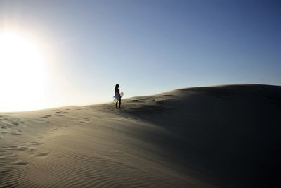 Full length of woman standing on desert against sky