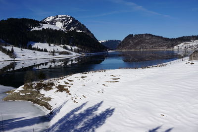 Scenic view of lake by snowcapped mountains against sky