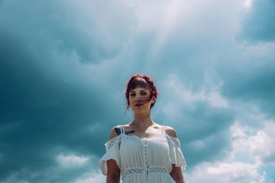 Low angle view of young woman standing against sky