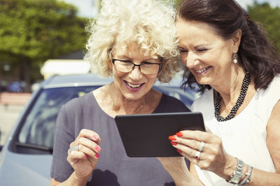 Happy senior women using digital tablet outdoors