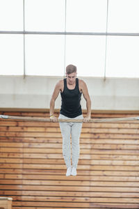 Full length of gymnast exercising on kip at gym