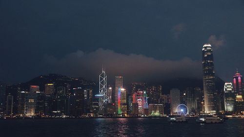 Illuminated buildings in city against sky at night