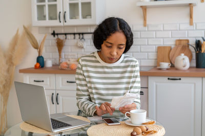 Portrait of young woman using laptop at home