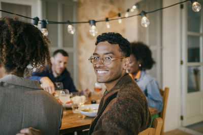 Portrait of smiling young man wearing eyeglasses sitting in patio during dinner party