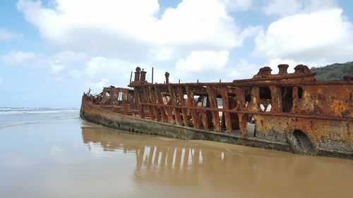 Panoramic view of abandoned ship in sea against sky