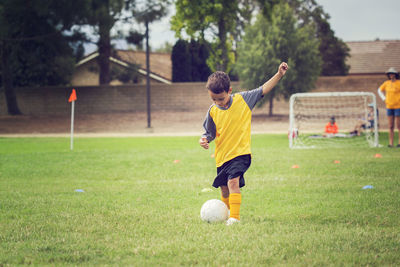 Boy playing soccer on grassy field