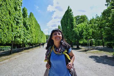 Young woman standing on road against trees