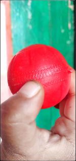 Close-up of hand holding red ball