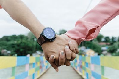 Close-up of couple holding hands on footbridge