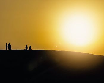 Silhouette people on mountain against sky during sunset