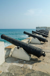 Scenic view old cannons at cape coast castle on sea against clear blue sky, ghana