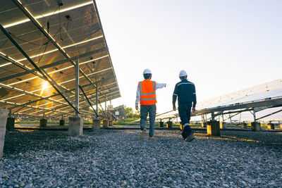 Rear view of men working at construction site against clear sky