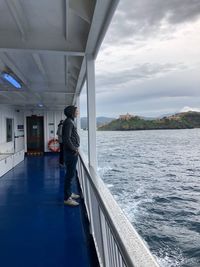 Man standing on boat in sea against sky