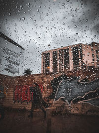 Buildings seen through wet glass window during rainy season