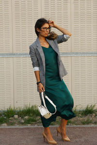 Woman looking away while standing on land against wall